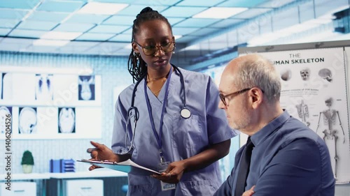 Expert and african american assistant provide medical services to patient at checkup, giving diagnostics report and medical records. Medical staff ensure healthcare exam on insurance. Camera A.