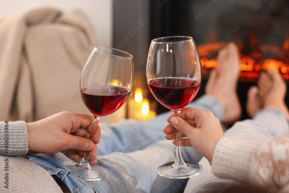 Couple with glasses of wine near fireplace on floor at home, selective focus