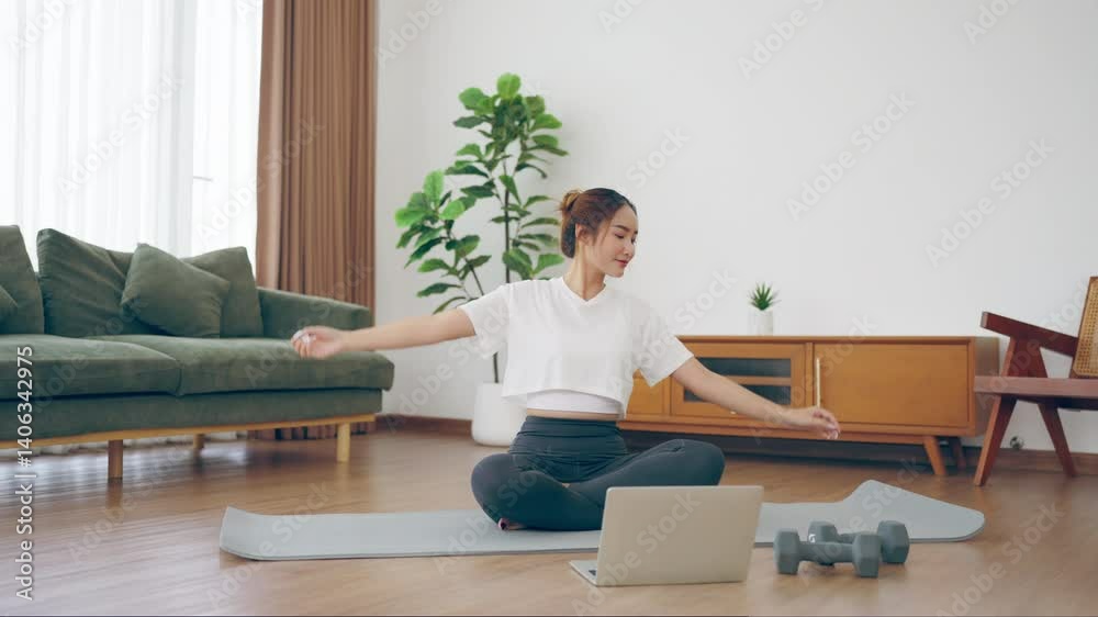 Happy young Asian woman practicing yoga and shoulder stretching at home sitting on floor in living room Happy young Asian woman practicing yoga and shoulder stretching at home sitting on floor in living room