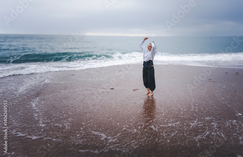 Obraz na płótnie Woman dancing on sandy seashore in rainy weather, mindful movement dance meditation concept w salonie