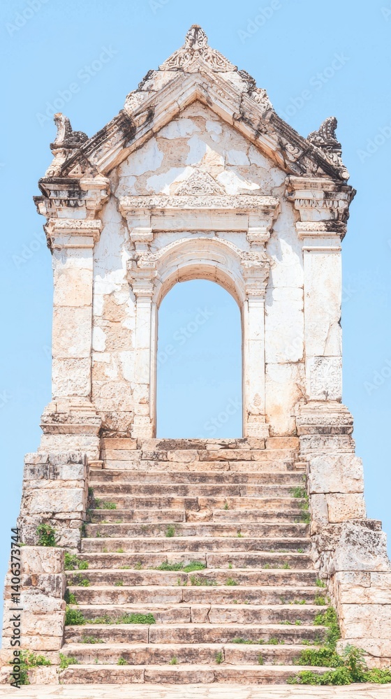 A weathered historical structure with an archway and worn stone steps, set against a clear blue sky. A weathered historical structure with an archway and worn stone steps, set against a clear blue sky.