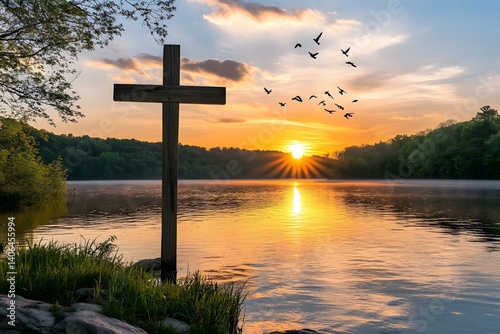 Wooden cross overlooking lake at sunset