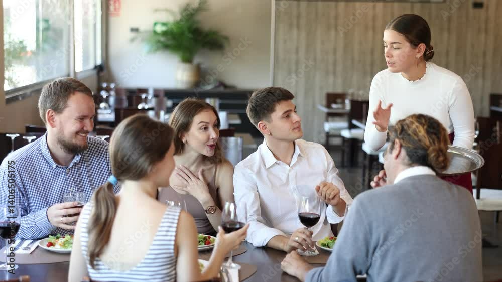 Young female waitress takes order from group of male and female friends in restaurant Young female waitress takes order from group of male and female friends in restaurant