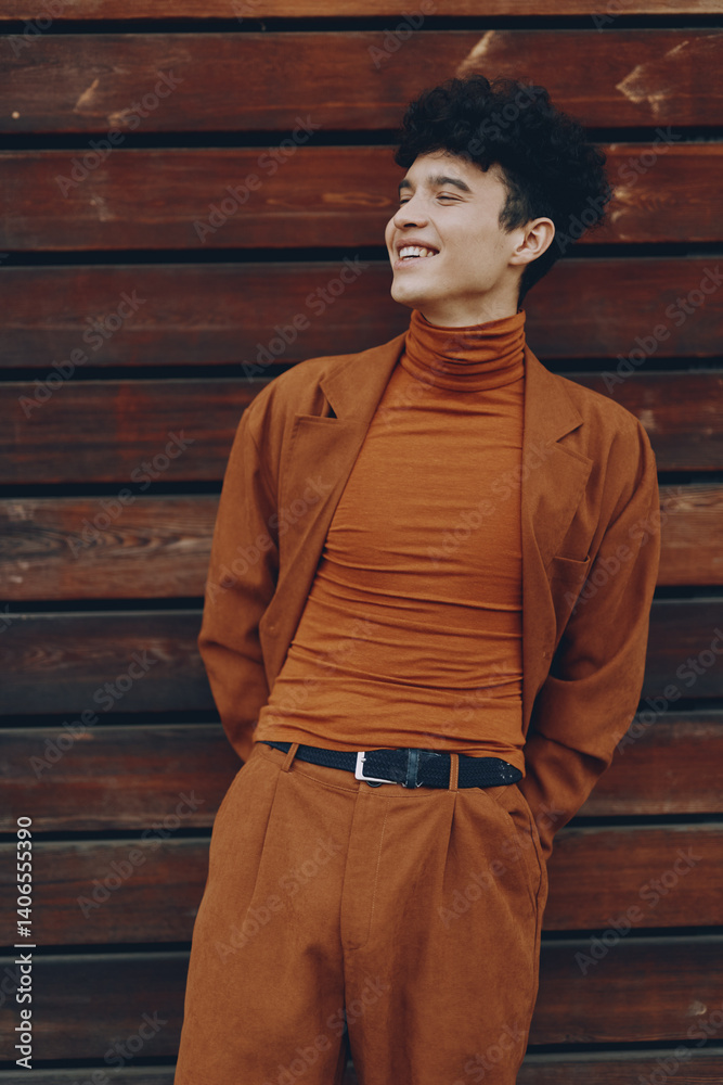 Stylish young man in warm toned outfit against wooden background, exuding confidence and charm