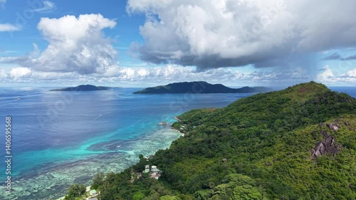 Praslin Island, Seychelles, with lush green hills, turquoise sea, and scenic tropical coastline under a clear blue sky.
