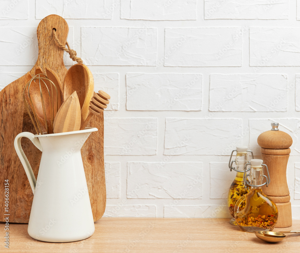 Kitchen utensils resting on wooden countertop by white brick wall