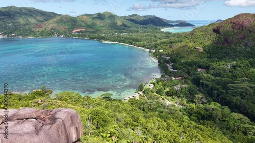 Praslin Island, Seychelles, with lush green hills, turquoise sea, and scenic tropical coastline under a clear blue sky.
