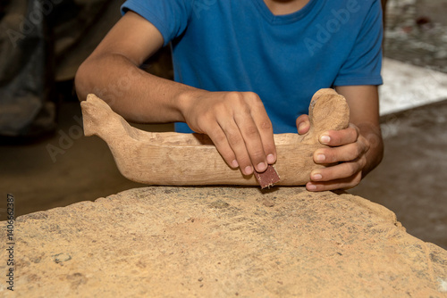 Hands sanding a piece of wood in a workshop. Artisanal process using sandpaper, meticulous craftsmanship. Person sanding wood. Waldorf education.