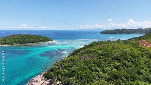 Praslin Island, Seychelles, with lush green hills, turquoise sea, and scenic tropical coastline under a clear blue sky.
