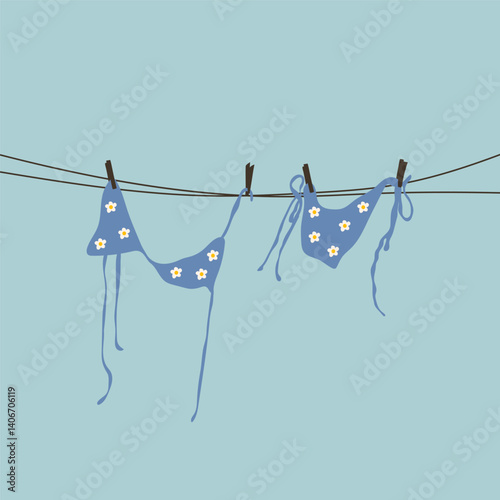 A blue floral swimsuit hanging on a clothesline under the sun