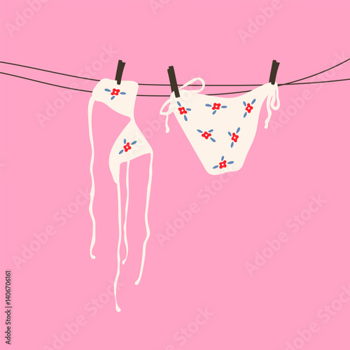 A white swimsuit with a delicate floral pattern hanging on a clothesline under the sun