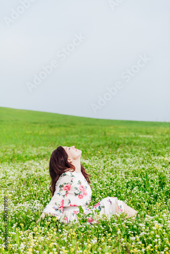 woman sitting in a field with flowers in spring and smiling