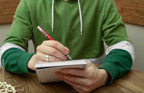 Student zapisuje coś w zeszycie, robi notatki photo