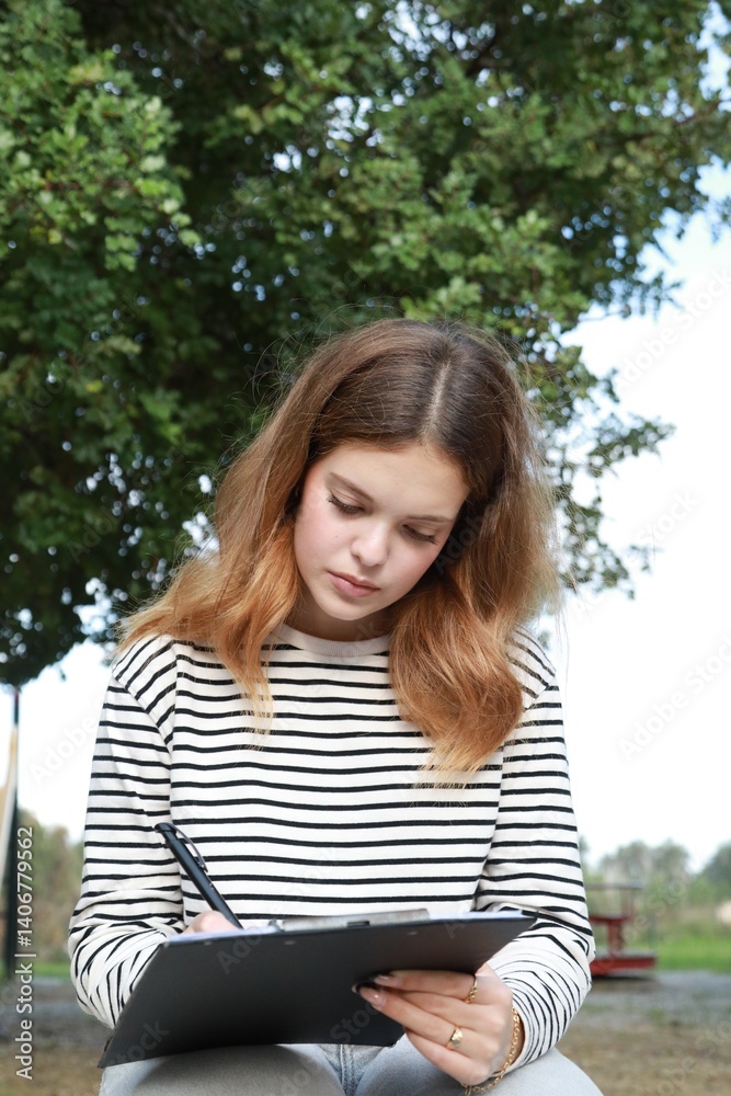 Girl Writes Musical Notes On A Sheet Music To Play Them With The Ukulele Girl Writes Musical Notes On A Sheet Music To Play Them With The Ukulele
