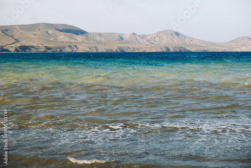 Brown waves washing Crimean coast with mountains in the background