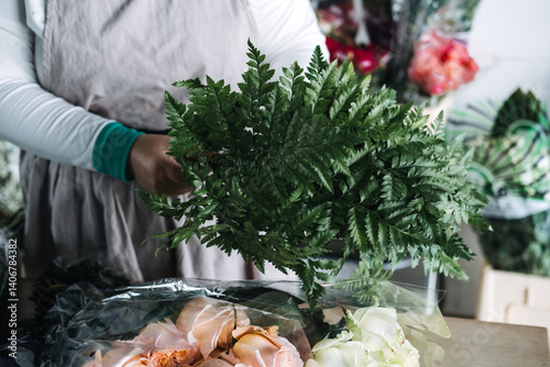 Florist arranging fresh greenery and roses on a worktable in a studio filled with blooms. Modern florist workshops, floral education, hands-on bouquet design, botanical craftsmanship