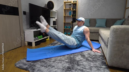 Exercises scissors legs for abdominal muscles. Young man doing pilates and workout in apartment. Workout at home. Sports lifestyle. Slow movement