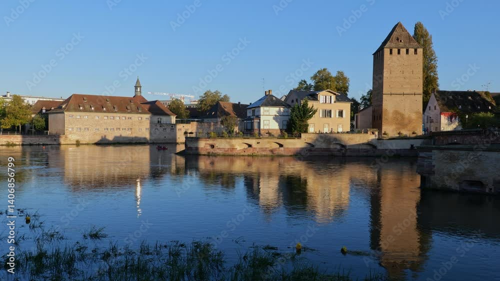 River Ill in city of Strasbourg at sunrise in Alsace, Grand Est, France. On the right medieval tower of Ponts Couverts - Covered Bridges. River Ill in city of Strasbourg at sunrise in Alsace, Grand Est, France. On the right medieval tower of Ponts Couverts - Covered Bridges.