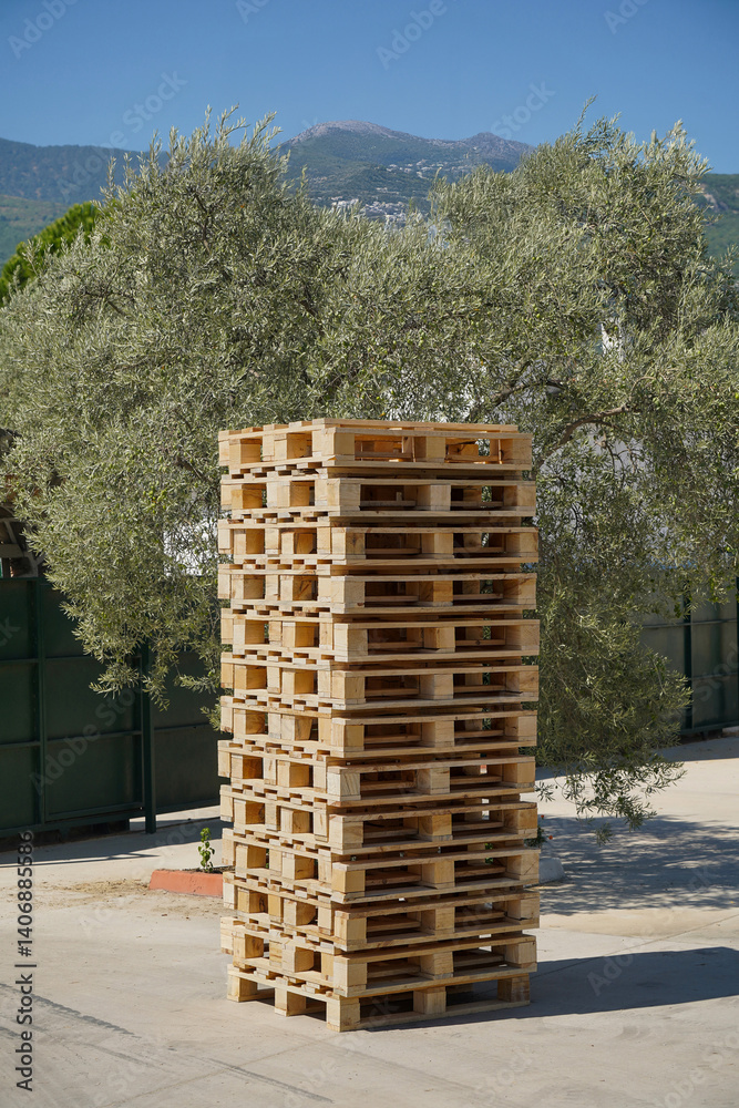 Large pile of wooden pallets outdoors at the factory loading dock.