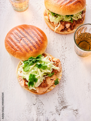 Two salmon burgers sit invitingly on a rustic wooden table, topped with crisp greens and herbs. Glasses nearby hint at a warm, sunlit gathering, perfect for sharing good food and laughter