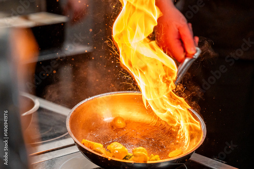Wallpaper Mural A chef's hand flames up in a frying pan filled with vegetables, creating a dramatic fire effect. The kitchen setting is dynamic and highlights the excitement of cooking. Torontodigital.ca