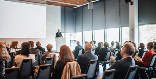 Speaker giving a talk in conference hall at business event. Rear view of unrecognizable people in audience at the conference hall. Business and entrepreneurship concept
