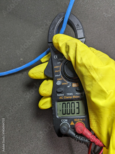 Technician using a clamp meter to measure electrical current on a blue wire