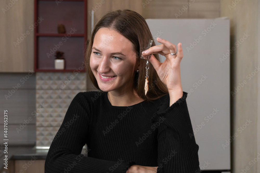 Happy homeowner smiling while holding keys to new apartment, showcasing house-shaped keyring and celebrating successful real estate purchase and mortgage approval