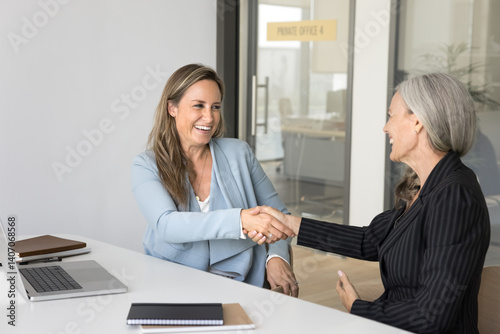 Collaboration across generations. Smiling women business partners handshaking at work office confirm successful deal. Grateful younger intern appreciate senior mentor for help consultation. Copy space