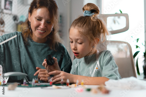 DIY workshop at home where young girl learns jewelry-making with resin. Hands-on project allows her to experiment with colors and textures, making unique handmade pieces.