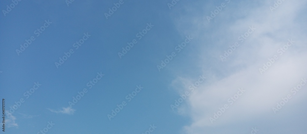 Obraz premium Serene Sky with Scattered Clouds. Blue Sky and Soft Cloudscape. Tranquil Sky with Light Clouds Background.