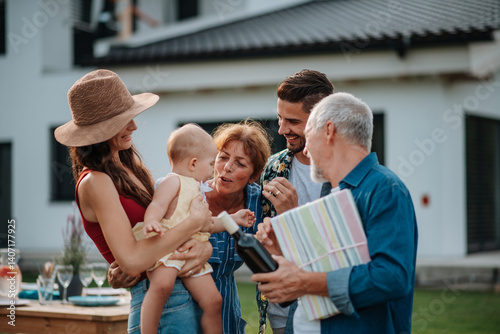 Parents welcoming their son, daughter-in-law, and baby at a family barbecue.