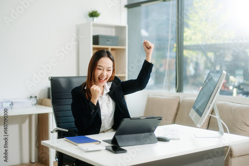 Asian business woman are delighted and happy with the work they do on their tablet, laptop and taking notes photo
