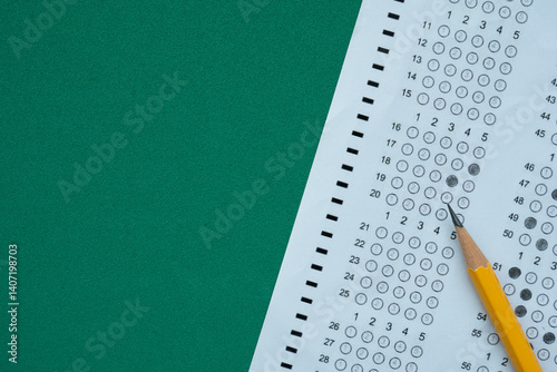 close up yellow pencil on answer sheets with green background, education concept