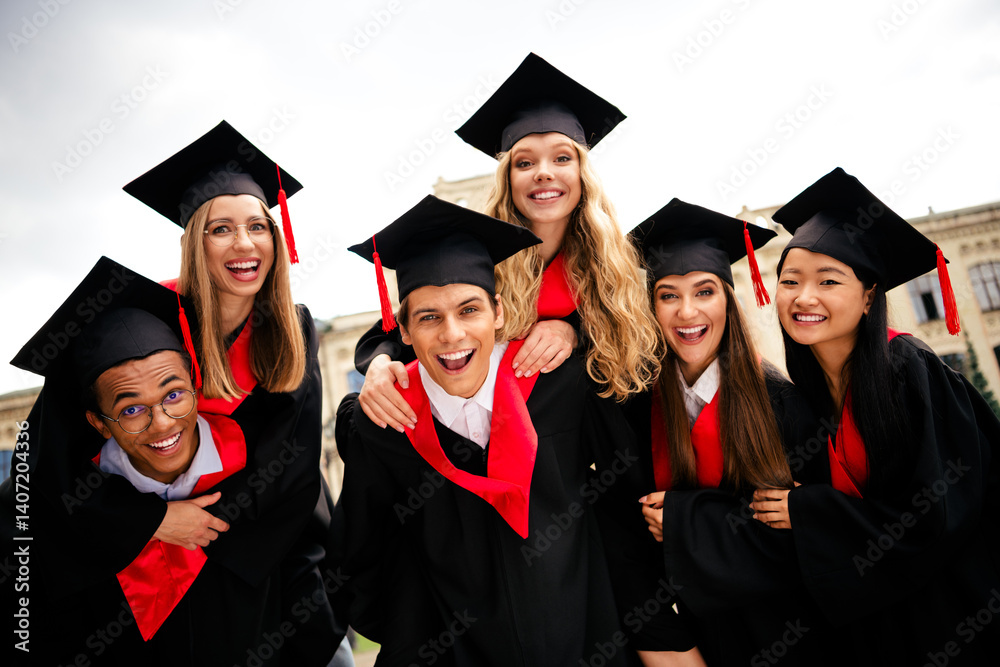 Joyful college graduates in traditional caps and gowns celebrating their success together outdoors on a sunny summer day. Joyful college graduates in traditional caps and gowns celebrating their success together outdoors on a sunny summer day.