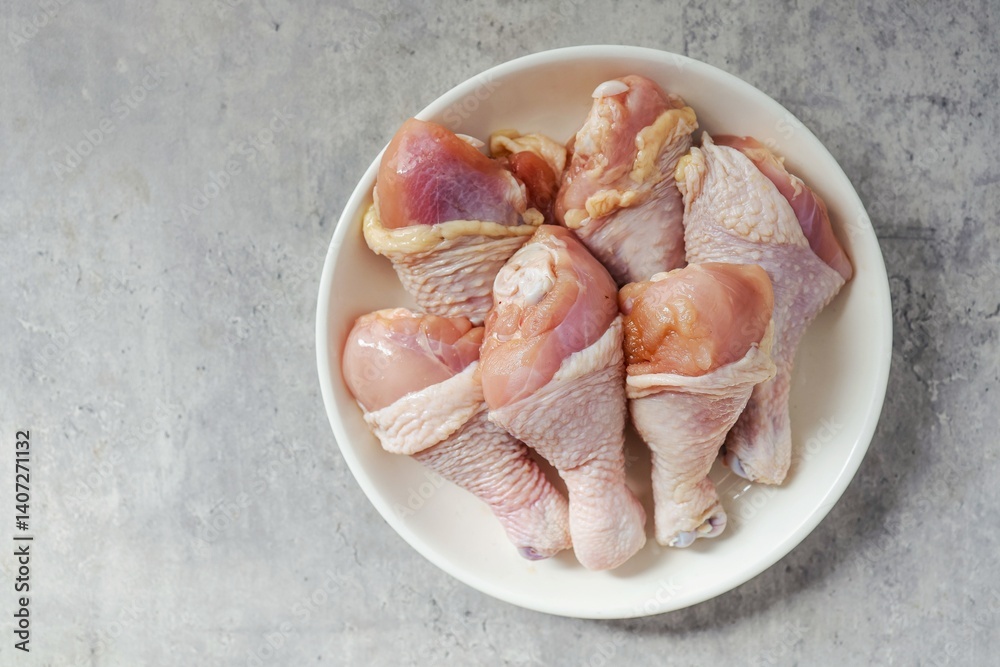fresh chicken drumsticks, raw chicken in white plate on cement background fresh chicken drumsticks, raw chicken in white plate on cement background