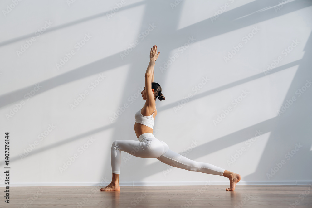 Fototapeta premium Yoga exercise. Beautiful young woman with slim body type is indoors