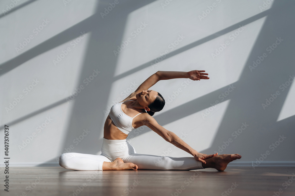 Fototapeta premium Professional yoga exercises. Beautiful young woman with slim body type is indoors