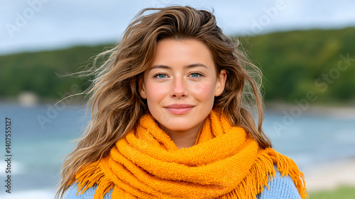 Woman with long wavy brown hair and blue eyes wearing a mustard yellow scarf outdoors