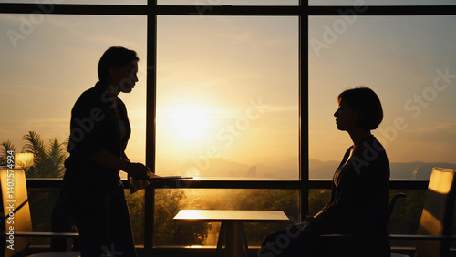 Silhouette of Two figures: Silhouetted figures engage in an intimate conversation against the backdrop of a stunning sunset, hinting at the depth of their connection and shared moment.