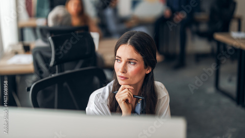 Focused Businesswoman in Office Thinking While Using Computer at Desk