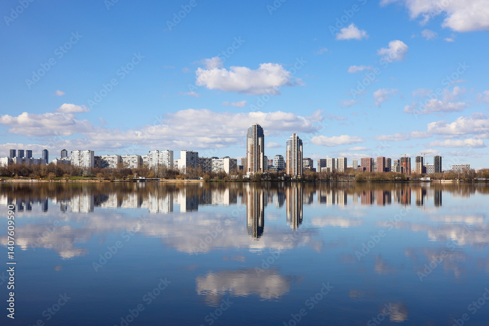 View to the city high rise buildings on river bank. Urban landscape with skyscrapers reflected in water