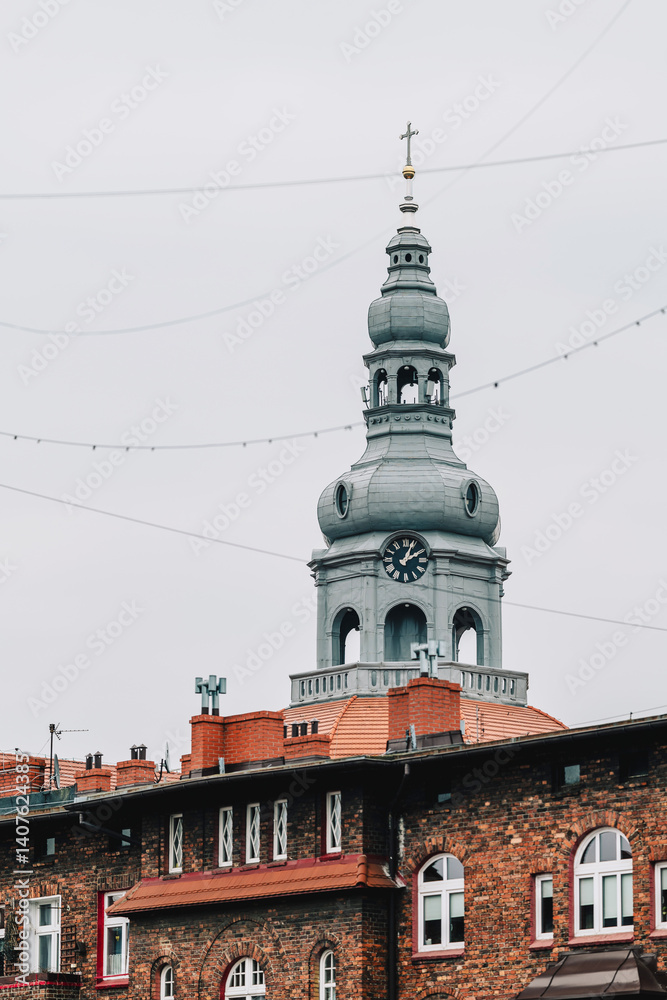 Old brick tenement houses in a workers' housing estate. Church tower in the background. Katowice, Nikiszowiec. Poland
