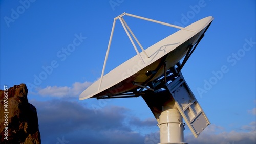 Large parabolic aerospace radar antenna directing toward a clear blue sky with fluffy clouds, symbolizing advancements in telecommunications and satellite technology photo