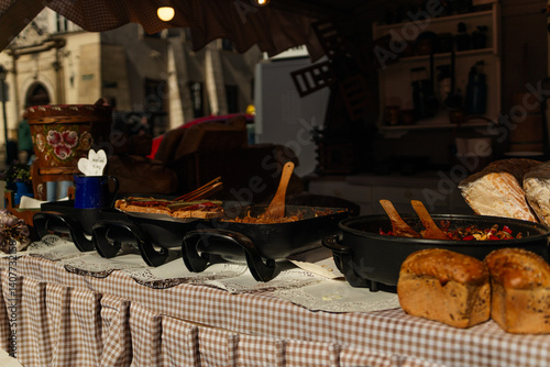 Obraz na płótnie A charming market stall displaying an assortment of freshly baked bread. The stall is adorned with decorative elements, showcasing a variety of artisanal loaves. The scene gives a rustic, warm feel w salonie