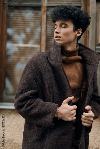 Bild auf Leinwand Fashionable man in a brown coat and turtleneck sweater posing in front of an old