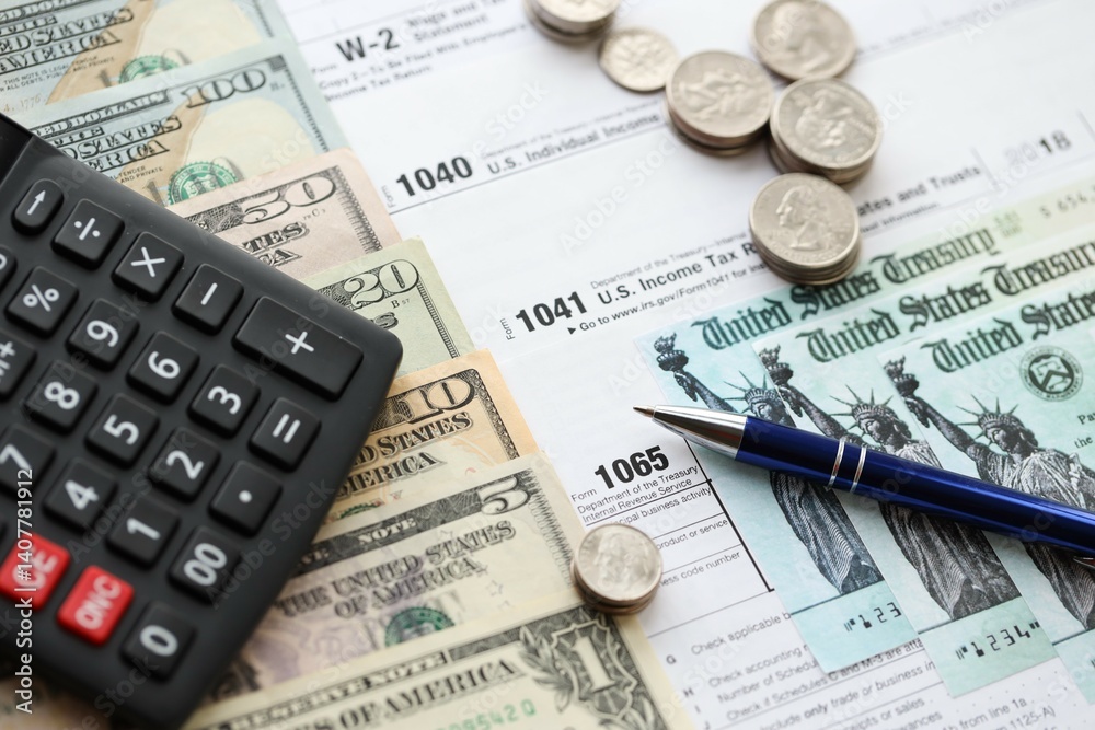 American US dollars money bills and coins with pen and calculator on IRS tax form blanks American US dollars money bills and coins with pen and calculator on IRS tax form blanks