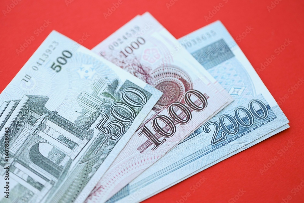 North Korean won money bills in big amount lies on red color table close up North Korean won money bills in big amount lies on red color table close up
