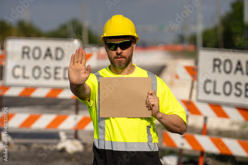 No trespassing. Construction worker with outstretched hand showing stop gesture warning. Stop sign in hands of worker. Concept he warns of danger. An engineer holds up an empty billboard near roadwork