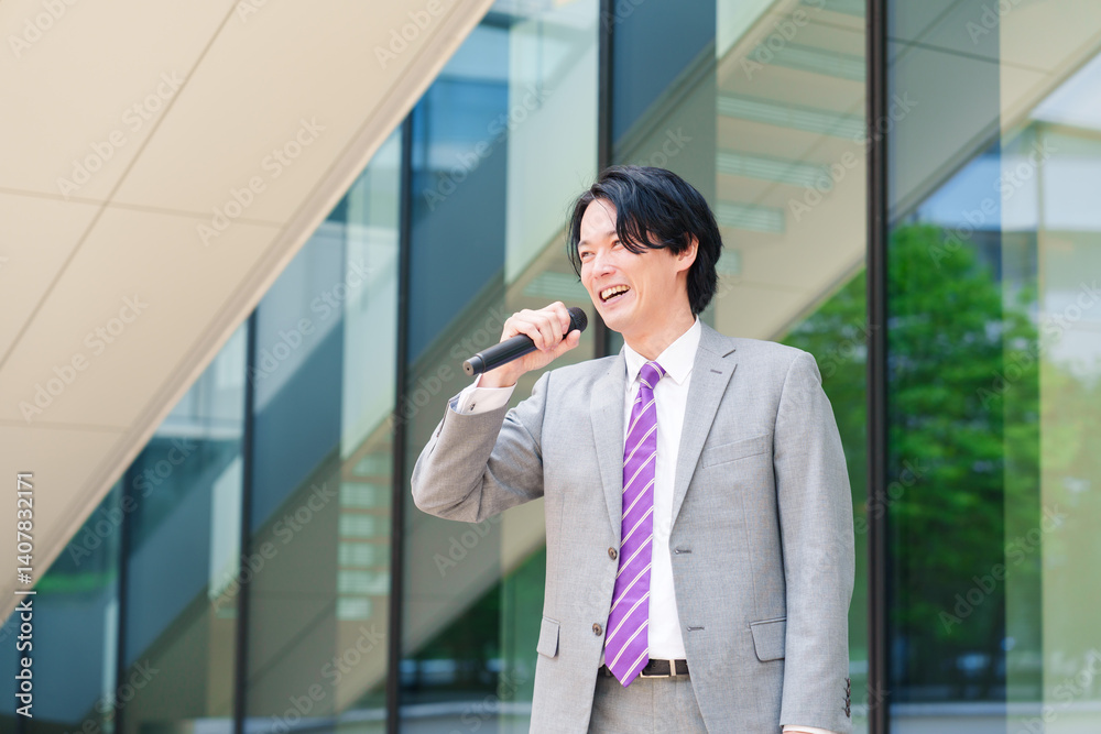 マイクを使って街なかで演説をするスーツを着た男性 マイクを使って街なかで演説をするスーツを着た男性